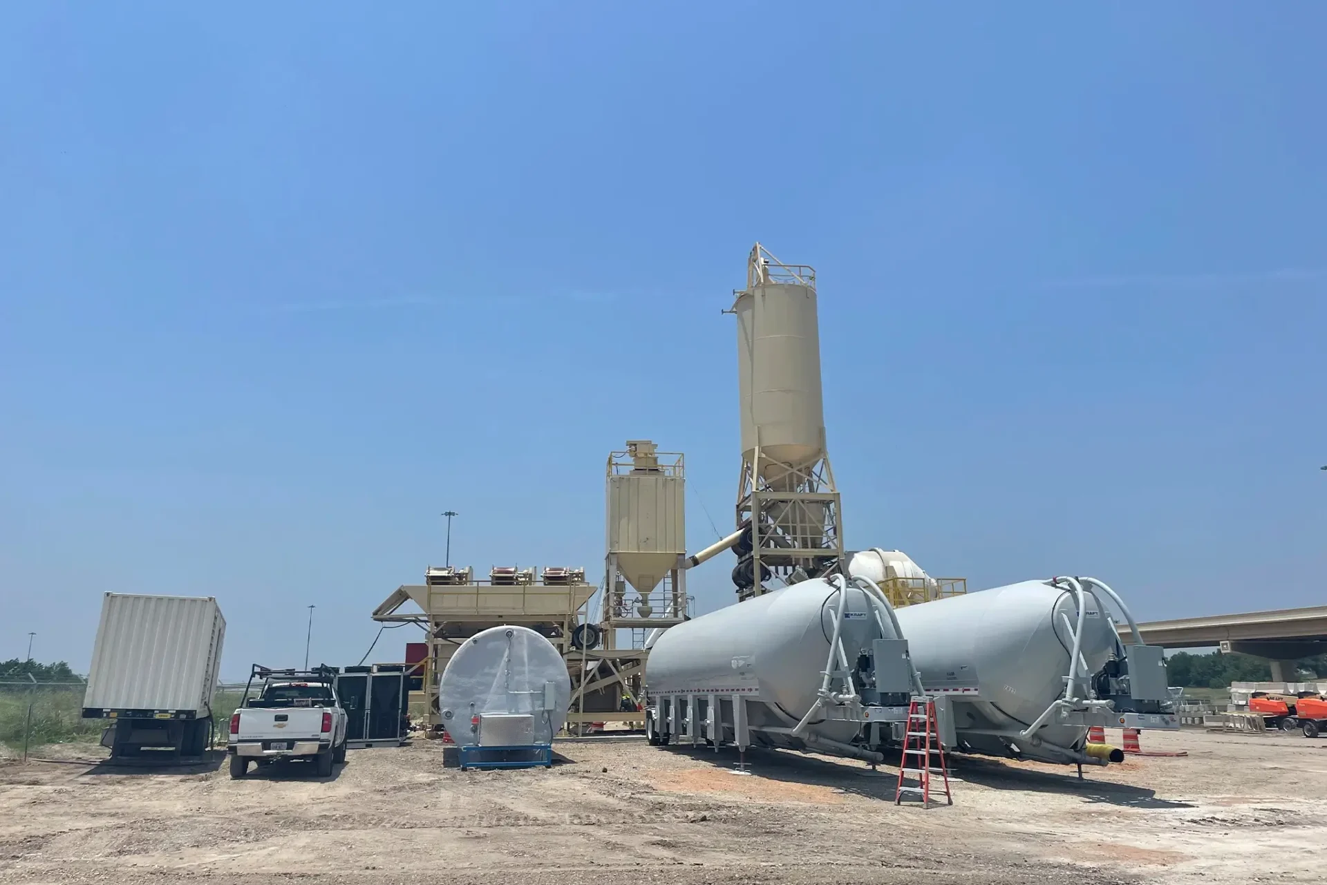A truck is parked next to cement trucks.